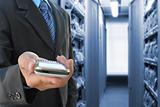 businessman hand holding mobile phone in the communication and internet network server room