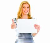 Smiling teen girl holding blank paper and showing thumbs up

