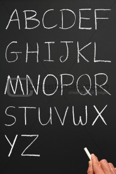 The alphabet in capitals written with white chalk on a blackboar