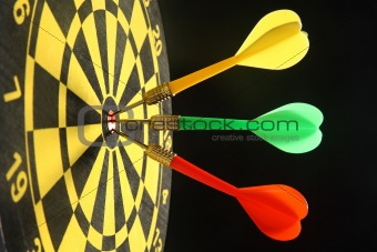 Three colourful darts in the bullseye.