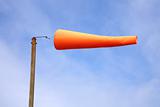 An orange windsock, blowing in a strong wind.
