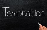 Writing temptation with white chalk on a blackboard.