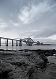 Black and White Forth Rail Bridge with foreground rocks in Scotland