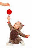 Cheerful baby playing stretching hand to Christmas ball
