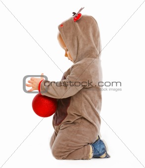 Baby playing with Christmas ball in profile
