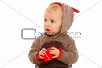 Lovely baby with little Christmas gift box looking in corner
