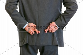 Closeup on hands with crossed fingers behind businessman back
