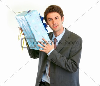 Modern businessman shaking present box trying to guess what's inside
