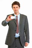 Smiling modern businessman showing business card
