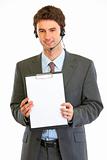 Smiling modern businessman in headset showing blank clipboard
