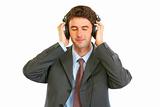 Happy man in business suit listening music in headphones
