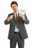 Happy modern businessman pointing on packs of dollars
