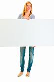 Full length portrait of teen girl holding blank billboard
