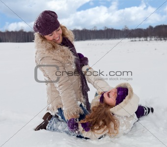 Woman and little girl having fun in the snow