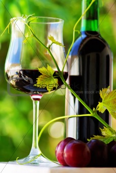 Glass and bottle of red wine with red fruits