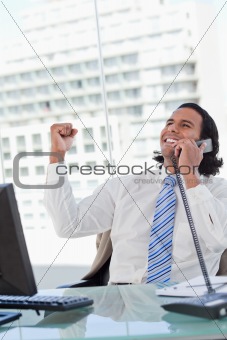 Portrait of a delighted businessman on the phone with the fist up