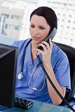 Portrait of a female doctor on the phone while using a monitor