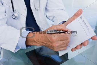 Close up of a male doctor showing a blank prescription sheet