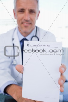 Portrait of a male doctor showing a blank prescription sheet