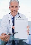 Portrait of a doctor showing a blank prescription sheet
