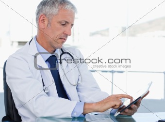 Serious doctor working with a tablet computer