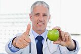 Doctor showing an apple with the thumb up
