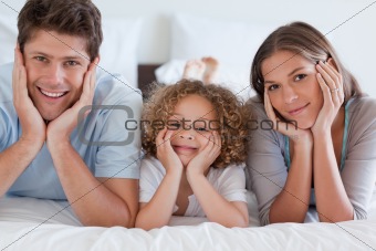 Parents lying on a bed with their son