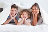 Happy family posing under a duvet