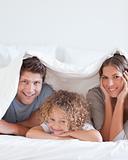 Smiling family lying in bed