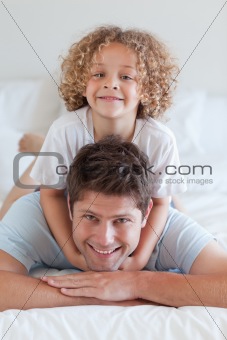 Smiling father and child lying on bed