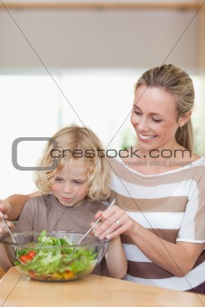 Mother and son stirring salad