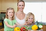Smiling woman with her children preparing salad