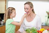 Girl feeding her mother with tomato