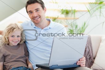 Father and son on couch with laptop