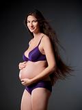 pregnant woman with very long brown hair in purple underwear