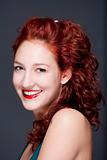 beautiful teenage woman with red hair smiling, looking - isolated on gray