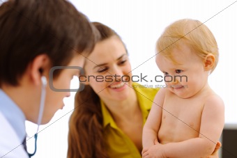 Pediatrician playing with hesitating baby on examination
