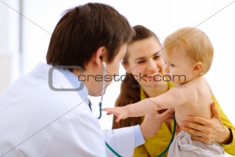 Interested baby stretching for stethoscope while being on examination
