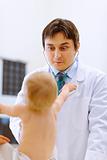 Pediatric doctor making fun faces for baby on examination
