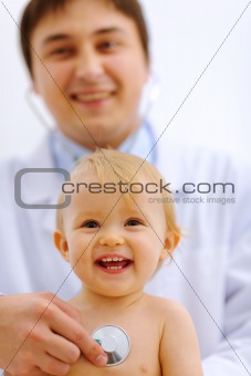Portrait of lovely baby being checked by a doctor using a stethoscope 
