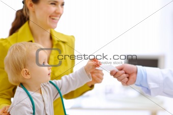 Mother and baby stretching for prescription in hand of pediatric doctor
