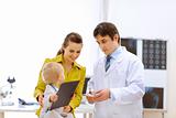 Pediatrician doctor explaining something to mother while baby playing on table
