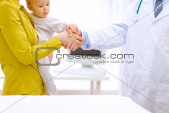 Closeup on doctor's mother's and baby's hands in handshake 
