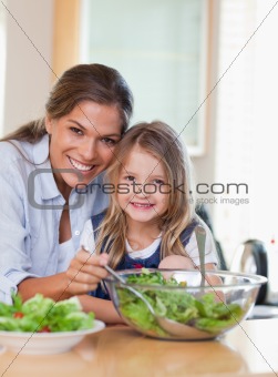 Portrait of a mother and her daughter preparing a salad