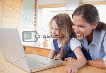 Smiling mother and her daughter using a notebook