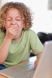 Portrait of a boy yawning while using a laptop