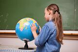 Focused schoolgirl looking at a globe