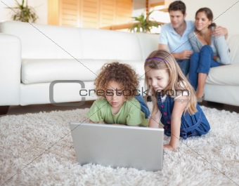 Children using a notebook while their parents are watching