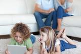 Children using a tablet computer while their parents are watching