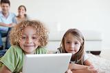 Smiling children using a tablet computer while their happy parents are watching